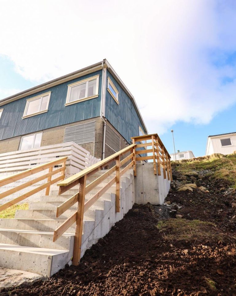 Betongtrappa og pallur steypt við síðuna av einum húsi