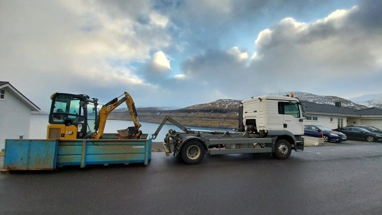 Krókbilur við lítlari gravmaskinu á einum konteineri